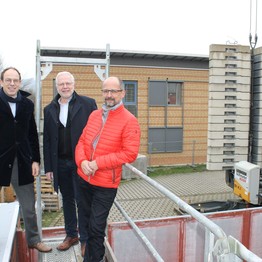 Drei Männer auf einem Baugerüst lächeln in die Kamera